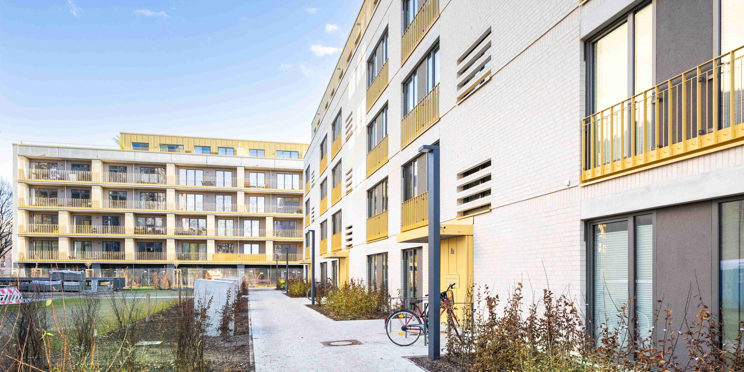 Nahaufnahme der Gebäudeecke, die den Kontrast zwischen der weißen Fassade und den dunklen Fensterprofilen bei Tageslicht zeigt.