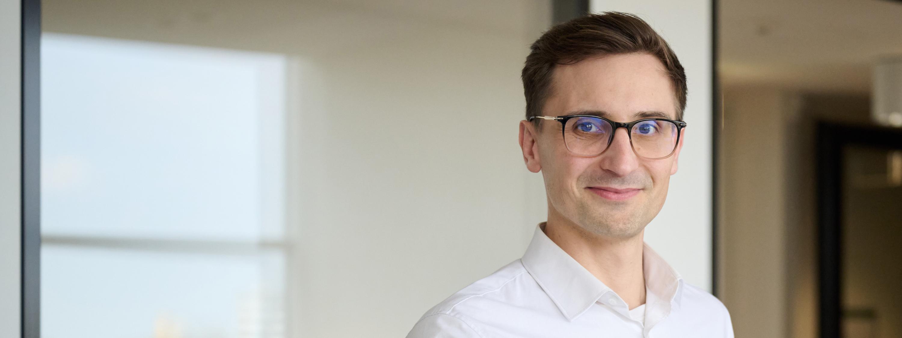 KAIFU-Vorstand Eric Yeung-Schüürmann an seinem neuen Arbeitsplatz an einen Schreibtisch . lächelt in die Kamera